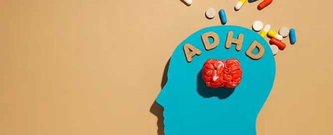 Blue profile silhouette of a head with a red brain and the letters ADHD above it, pills spilling outward to illustrate ADHD treatment awareness.